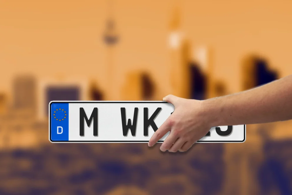 Nummernschild mit M wie München vor Stadtsilhuette